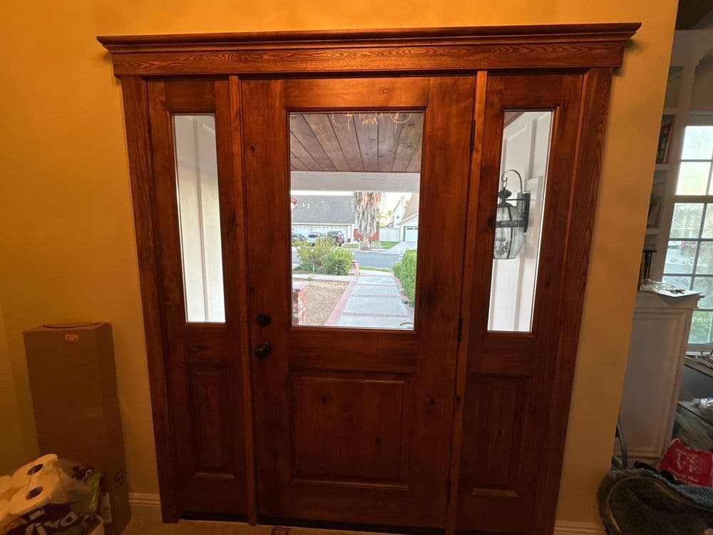 Wooden double front door with windows, inviting entrance, and natural light.
